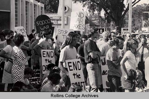 A large group of young students holding up papers signs   that protest the Vietnam war